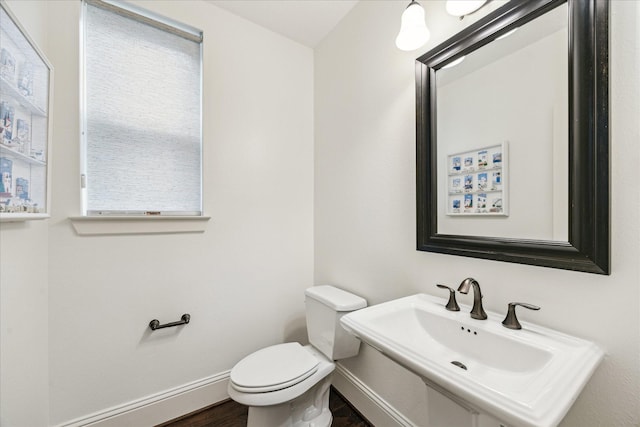 bathroom with toilet, baseboards, a sink, and wood finished floors