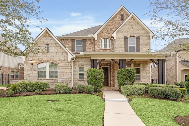 french country style house featuring a front lawn, a shingled roof, and brick siding