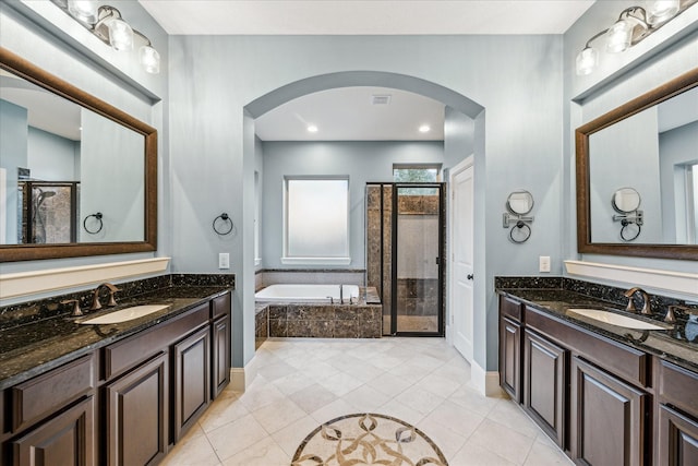 bathroom featuring a stall shower, two vanities, a sink, and a bath