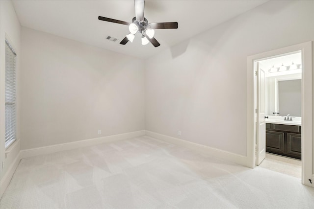 unfurnished bedroom with light carpet, ensuite bath, baseboards, and a sink