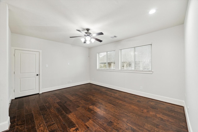 empty room featuring dark wood-style floors, ceiling fan, visible vents, and baseboards