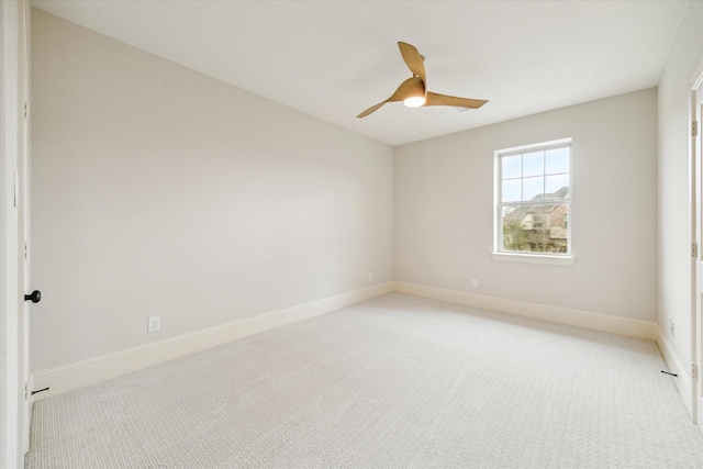 spare room with a ceiling fan, light colored carpet, and baseboards