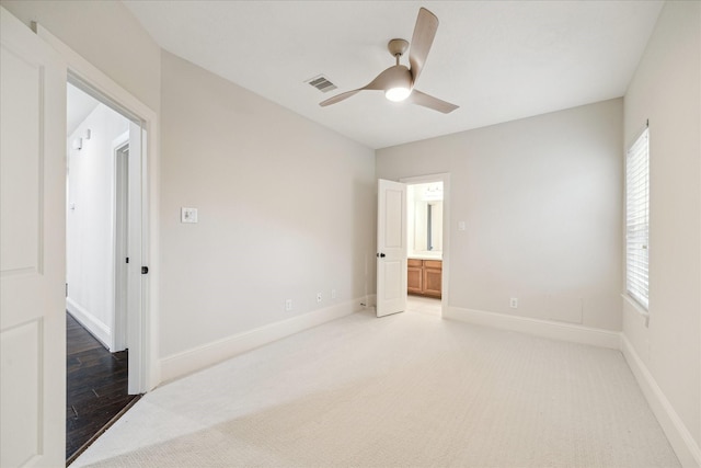 empty room featuring a ceiling fan, light colored carpet, visible vents, and baseboards