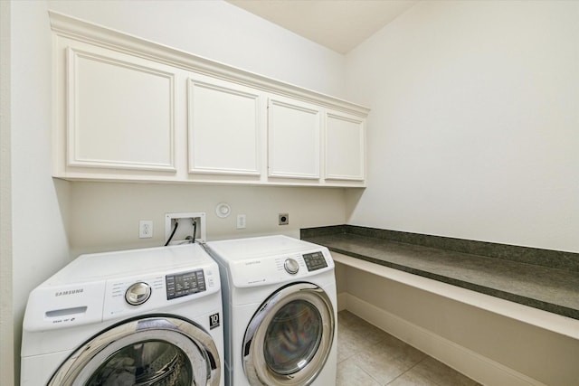 washroom with cabinet space, baseboards, washer and dryer, and light tile patterned flooring