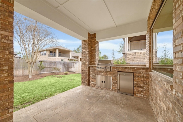 view of patio / terrace featuring a fenced backyard, grilling area, and an outdoor kitchen