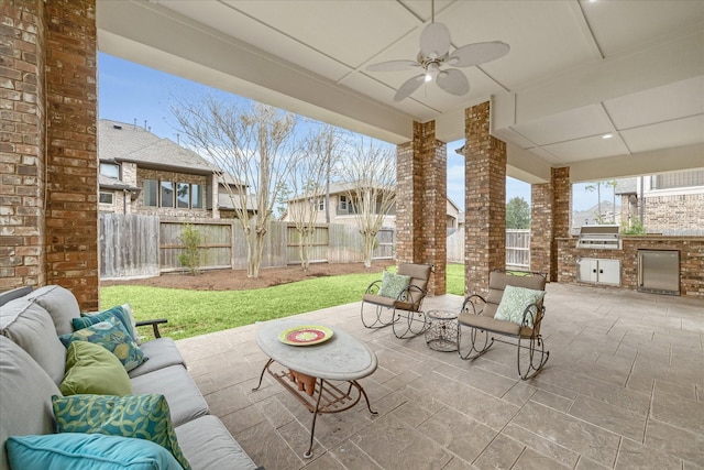 view of patio with area for grilling, ceiling fan, a fenced backyard, exterior kitchen, and outdoor lounge area