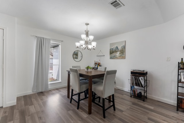 dining room with visible vents, a notable chandelier, baseboards, and wood finished floors