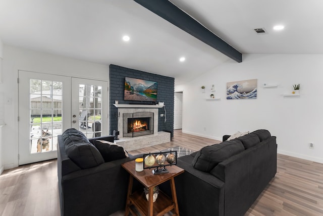 living room with light wood-type flooring, a fireplace, and visible vents