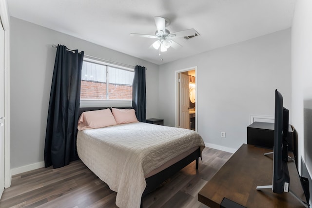 bedroom with wood finished floors, a ceiling fan, visible vents, baseboards, and ensuite bath