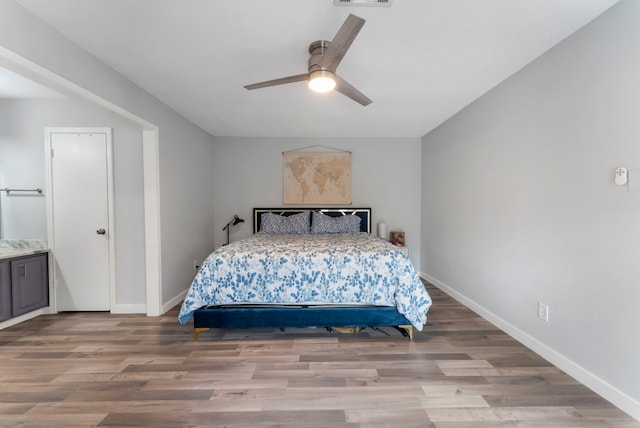 bedroom featuring a ceiling fan, visible vents, baseboards, and wood finished floors