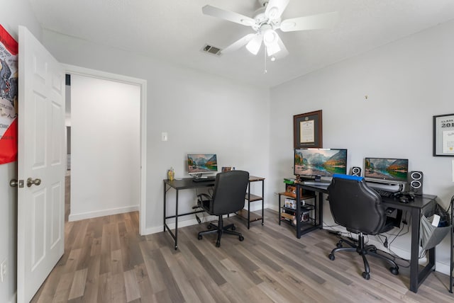 home office featuring a ceiling fan, visible vents, baseboards, and wood finished floors