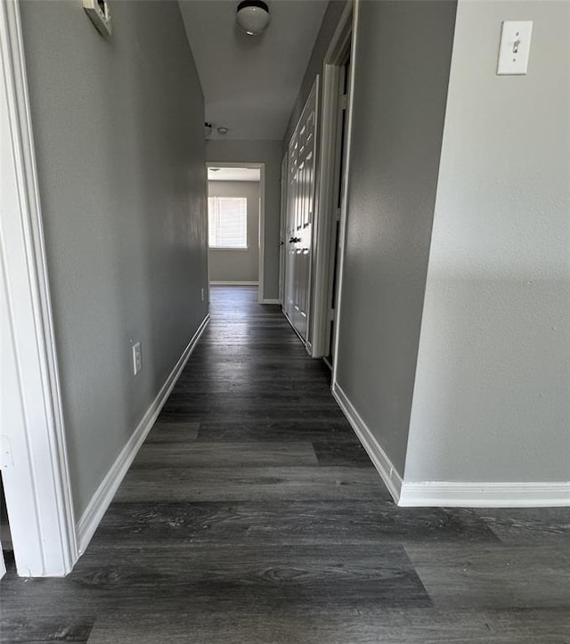 hallway with dark wood-style flooring and baseboards