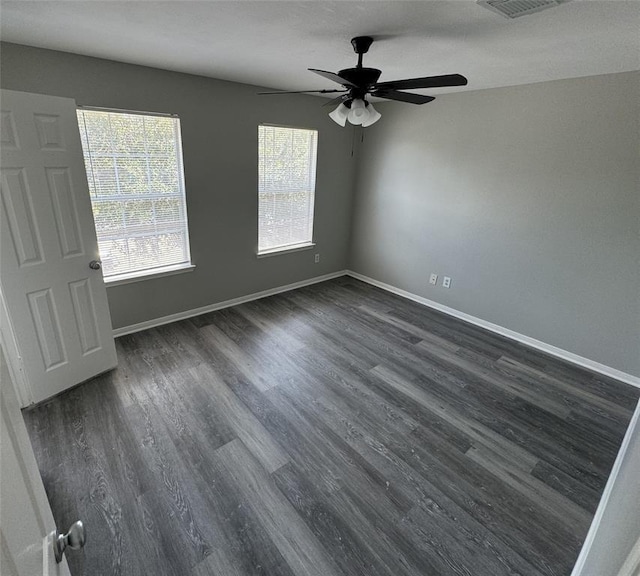 spare room featuring baseboards and dark wood finished floors