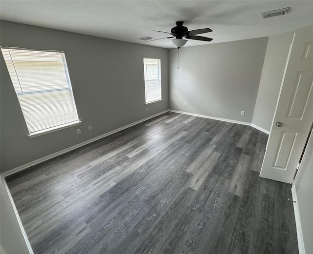 unfurnished room with a ceiling fan, dark wood finished floors, visible vents, and baseboards