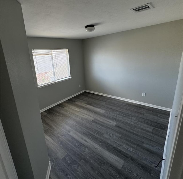 unfurnished room with baseboards, a textured ceiling, visible vents, and dark wood-style flooring