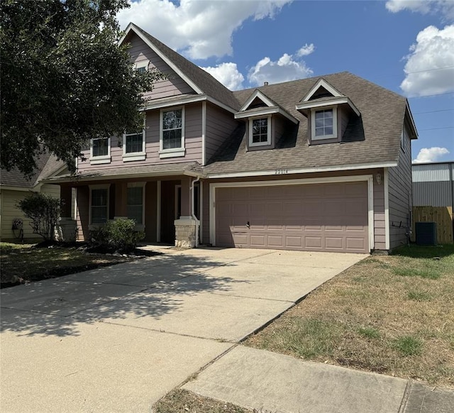 view of front of home featuring roof with shingles, driveway, an attached garage, and central AC unit