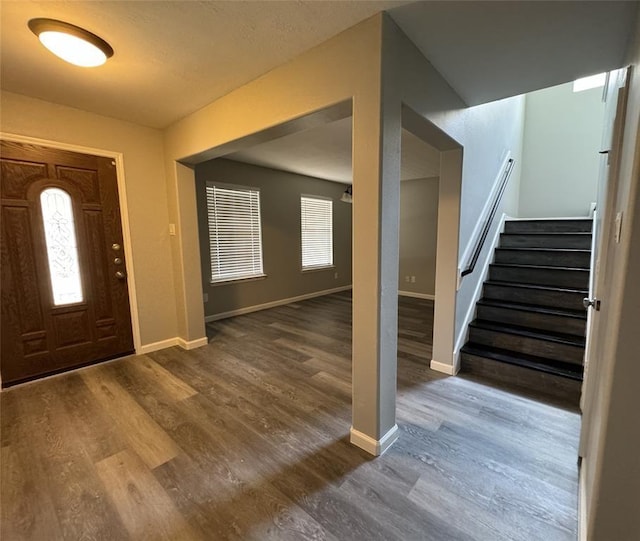 foyer with stairs, baseboards, and wood finished floors