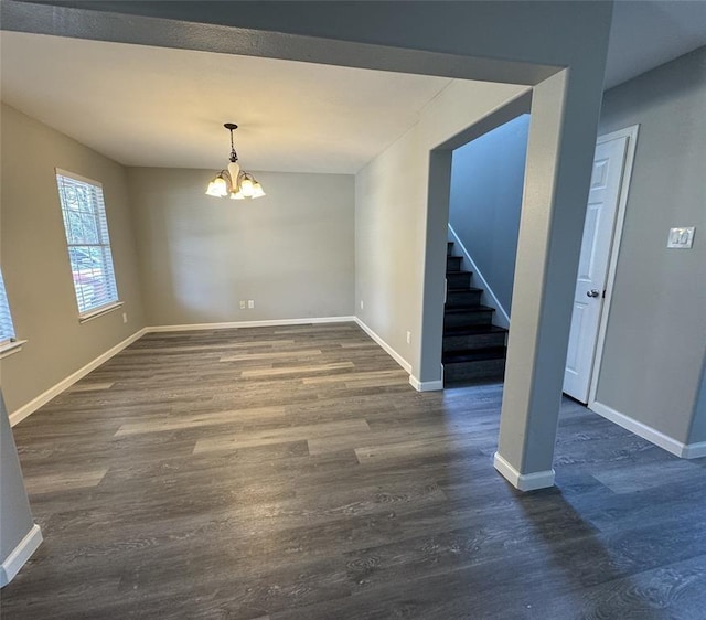 unfurnished dining area featuring an inviting chandelier, stairs, baseboards, and dark wood-style flooring