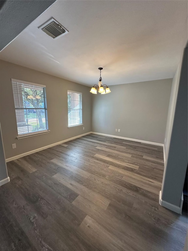 spare room featuring baseboards, visible vents, a chandelier, and dark wood-type flooring