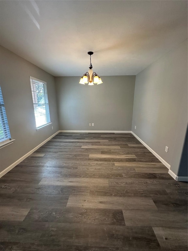 unfurnished dining area with dark wood-style floors, a chandelier, and baseboards