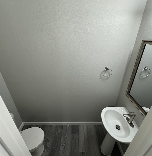 bathroom with a sink, wood finished floors, toilet, and baseboards