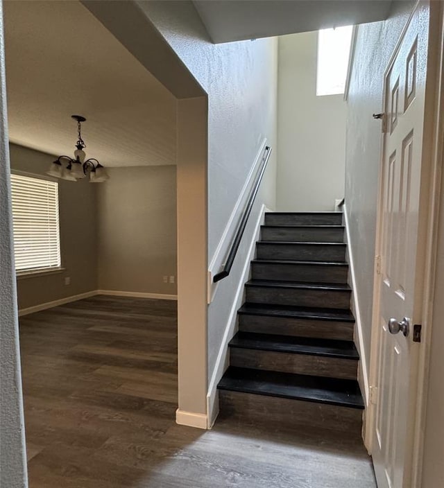 stairway with a chandelier, wood finished floors, and baseboards