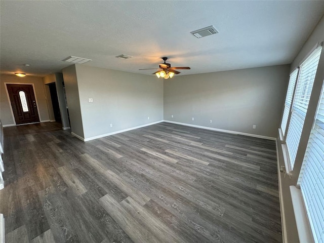 empty room featuring visible vents, baseboards, and dark wood-style flooring