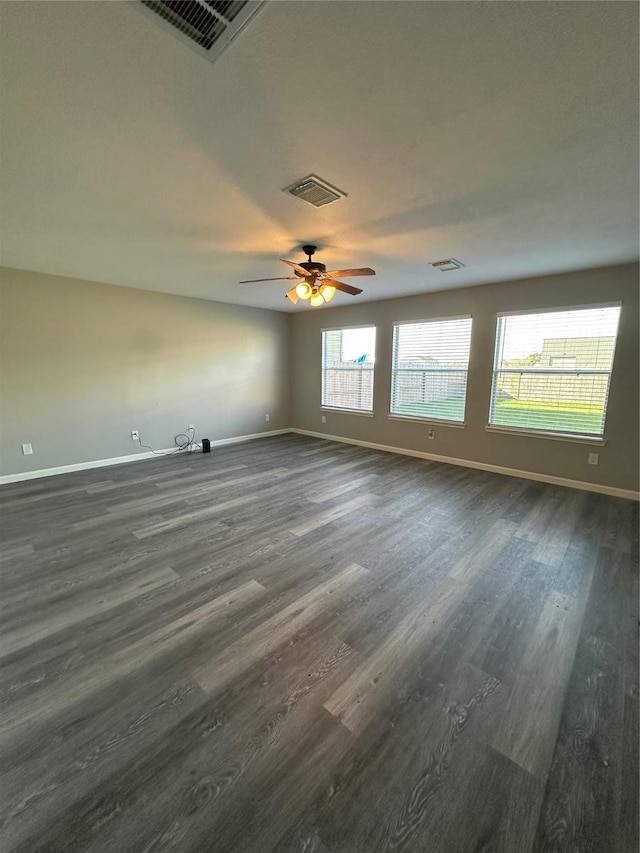 empty room featuring visible vents, dark wood finished floors, baseboards, and ceiling fan