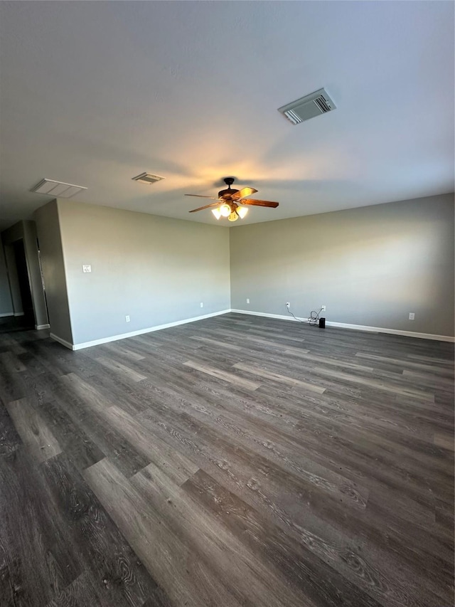 spare room with dark wood-style floors, visible vents, and baseboards