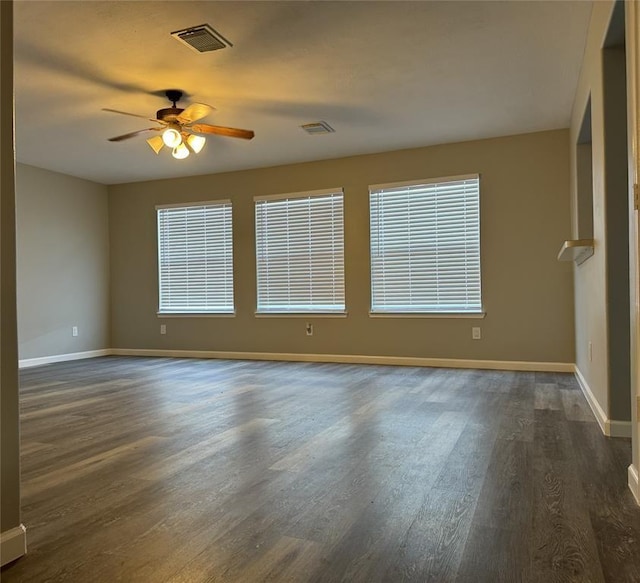 unfurnished room featuring dark wood-style floors, visible vents, and a ceiling fan