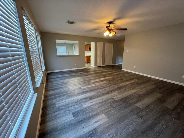 interior space featuring ceiling fan, a textured ceiling, dark wood-style flooring, visible vents, and baseboards