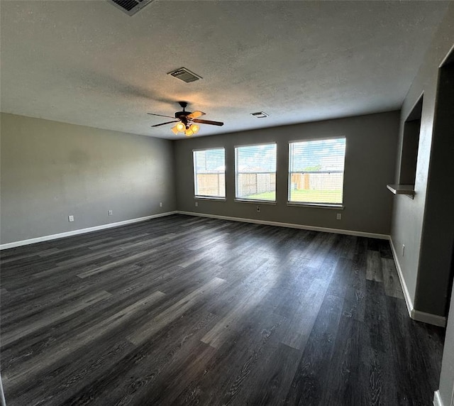 empty room with a textured ceiling, dark wood-type flooring, and baseboards