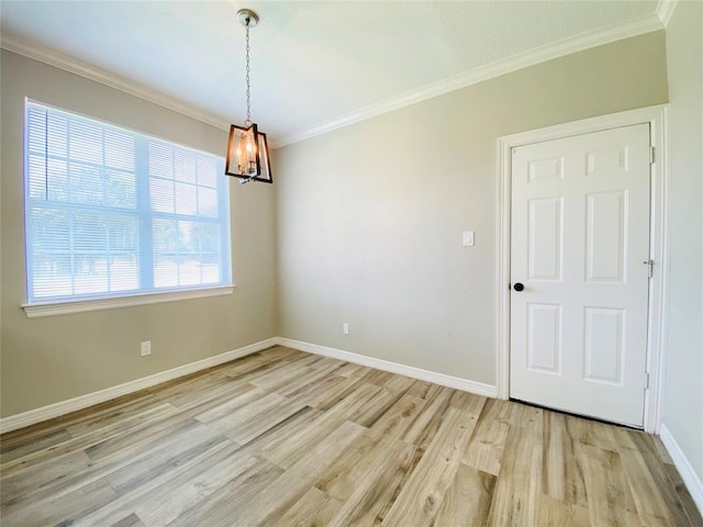 empty room featuring ornamental molding, a notable chandelier, light wood-style flooring, and baseboards