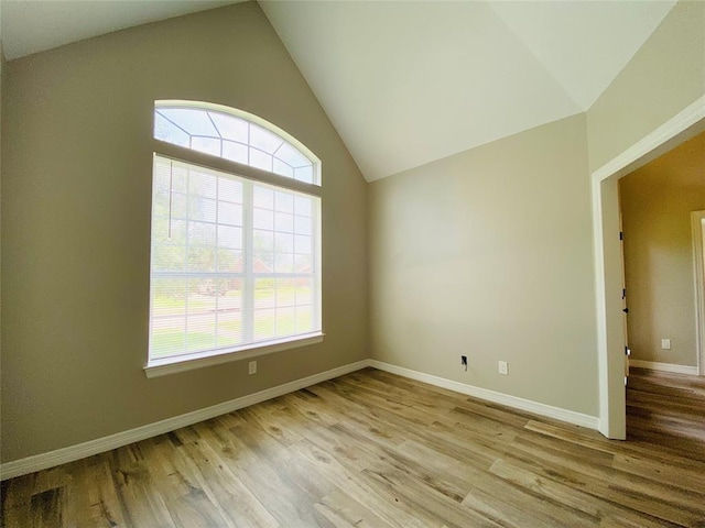 unfurnished room with lofted ceiling, light wood finished floors, and baseboards