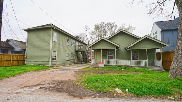 view of front of home with driveway, fence, and a porch