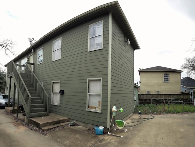 rear view of property with fence and stairs