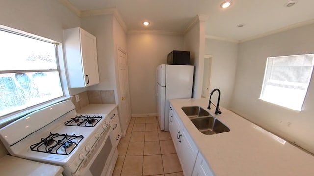 kitchen with a healthy amount of sunlight, white appliances, white cabinets, and a sink