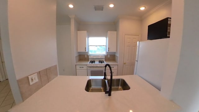 kitchen featuring white appliances, white cabinets, a sink, and light countertops