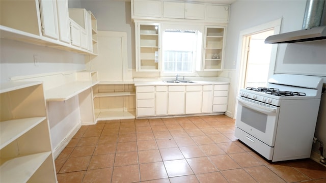 kitchen featuring a sink, white cabinetry, wall chimney exhaust hood, white gas range oven, and open shelves