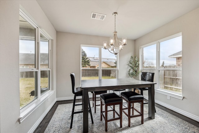 dining area featuring baseboards, dark wood finished floors, visible vents, and an inviting chandelier