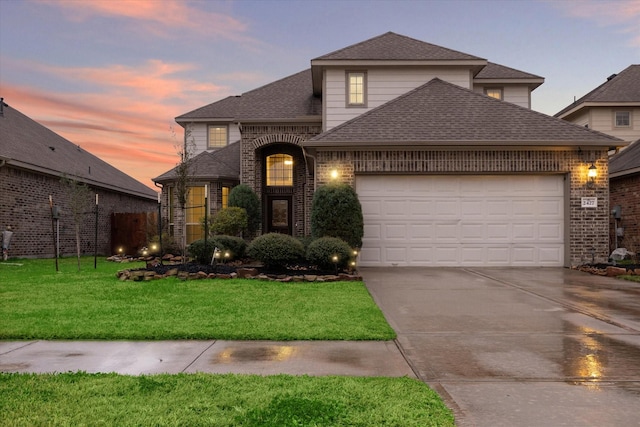 traditional-style house featuring an attached garage, brick siding, concrete driveway, roof with shingles, and a lawn