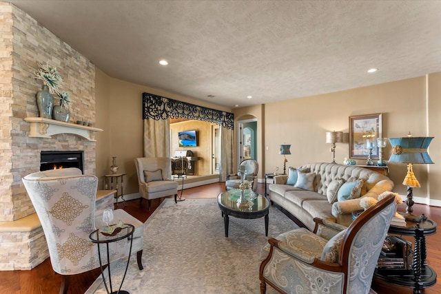 living room with arched walkways, wood finished floors, a textured ceiling, a fireplace, and recessed lighting