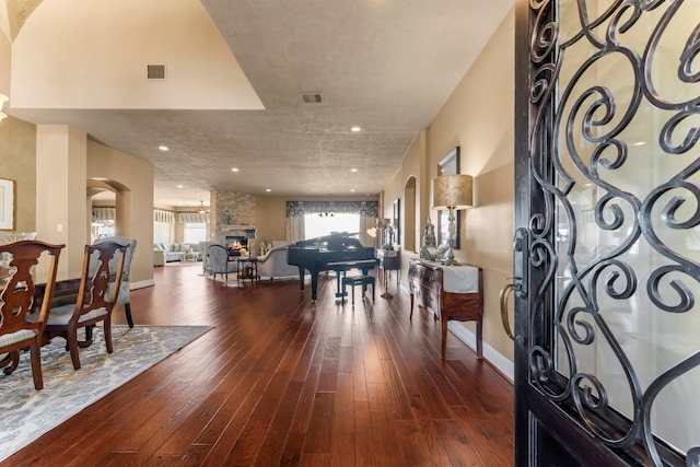 entryway featuring hardwood / wood-style flooring, visible vents, arched walkways, and a stone fireplace