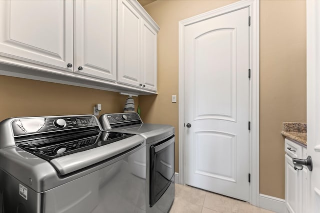 laundry room featuring light tile patterned floors, independent washer and dryer, cabinet space, and baseboards