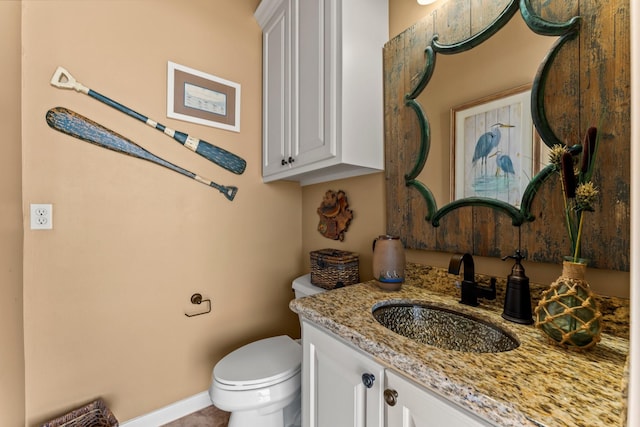 bathroom with toilet, baseboards, and vanity