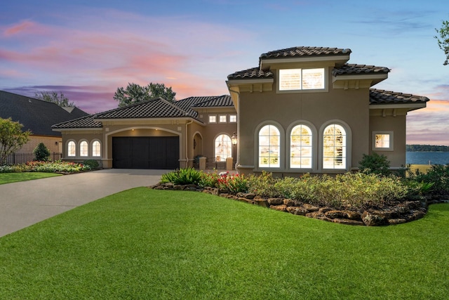 mediterranean / spanish house with concrete driveway, a front lawn, an attached garage, and stucco siding