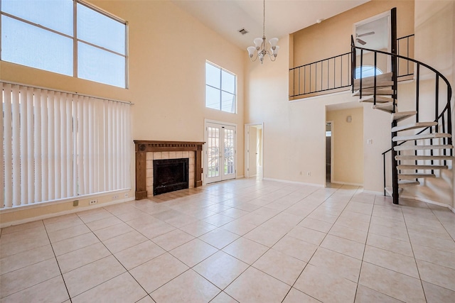 unfurnished living room featuring baseboards, a tiled fireplace, stairs, an inviting chandelier, and tile patterned floors