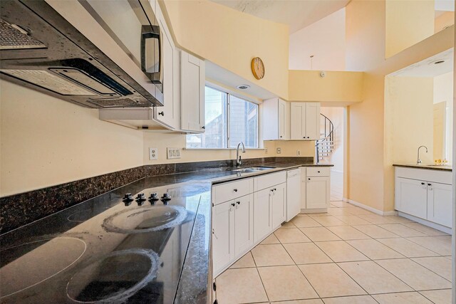 kitchen with a sink, dark countertops, dishwasher, and light tile patterned floors