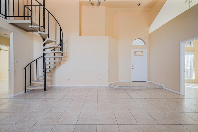 entryway with light tile patterned floors, baseboards, and a high ceiling