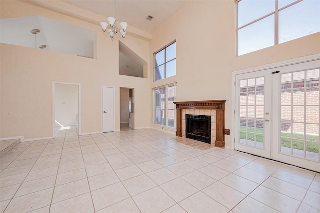 unfurnished living room with light tile patterned floors, baseboards, visible vents, an inviting chandelier, and a tiled fireplace